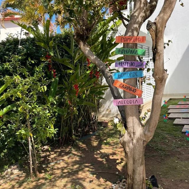 Árvore com placas coloridas: família, esperança, respeito, bondade, carinho e alegria